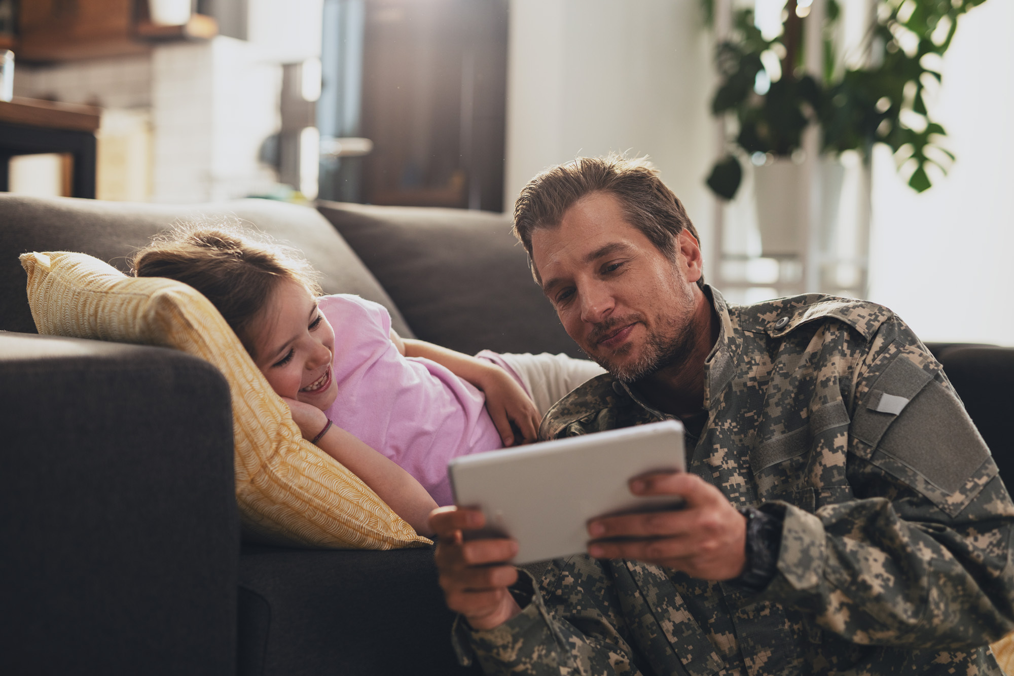 Father in military uniform on tablet with daughter