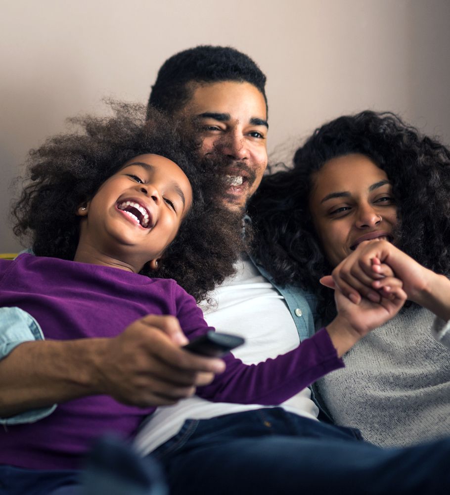 Mother, father and child laughing on sofa